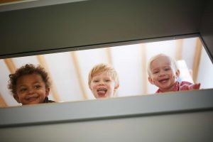 Drei Kinder die durch ein Fenster lachen